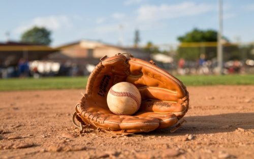 Baseball and glove on a baseball field, with blurred background of people