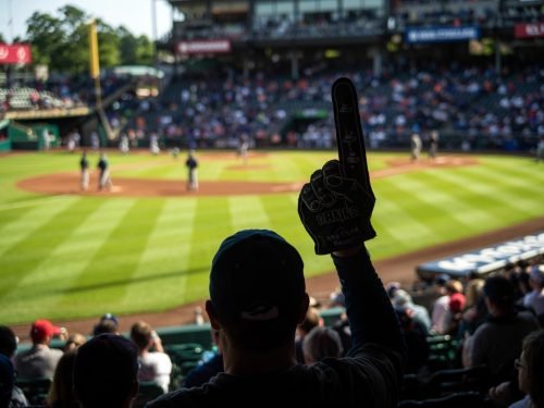 Baseball fan in stands with foam finger, watching the game