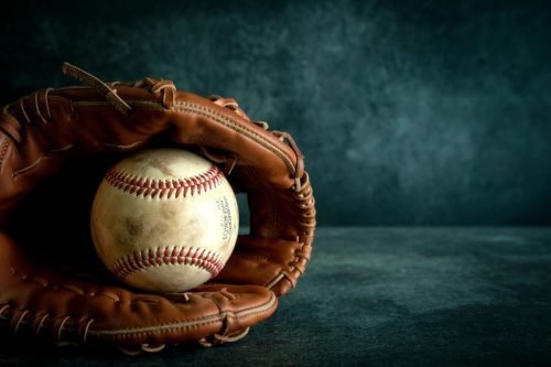 Baseball in a brown leather glove on a dark background