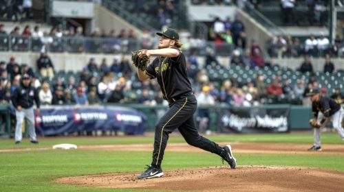 Baseball pitcher in black and gold uniform throws a pitch on the mound