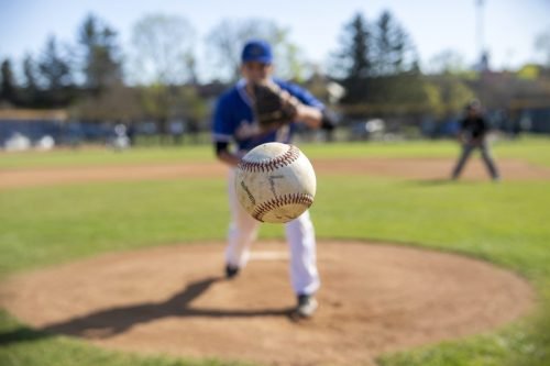 Baseball pitcher throwing a ball on a baseball field, with batter in background