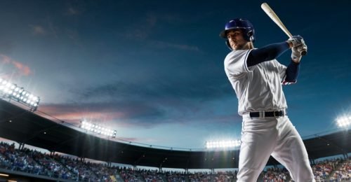 Baseball player in uniform swinging a bat in a stadium at night