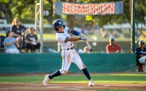 Baseball player swings bat, hitting a ball during a game