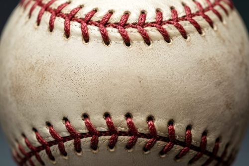 Close-up of a baseball showing red stitching on a white leather surface