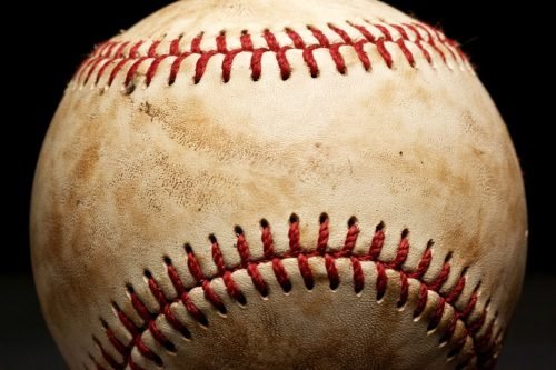 Close-up of a well-worn baseball with red stitching on a black background
