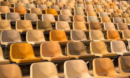 Rows of empty stadium seats in various shades of yellow