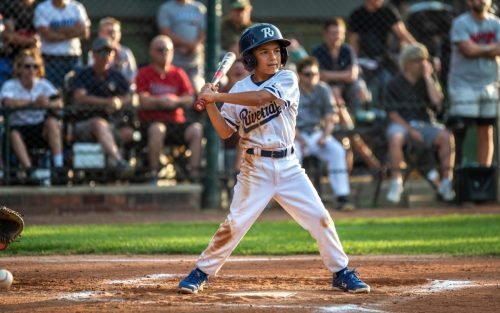 Young baseball player at bat, wearing a helmet and uniform, ready to hit
