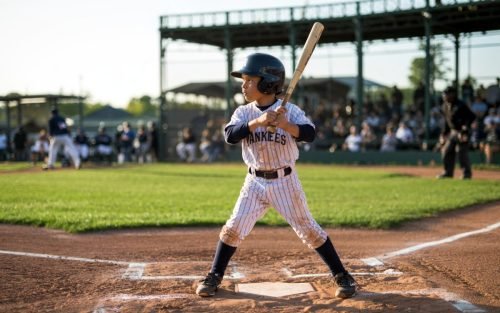 Young baseball player in Yankees uniform at bat, ready to hit